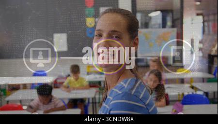 Smiling female teacher guiding students in elementary classroom, with floating digital icons Stock Photo