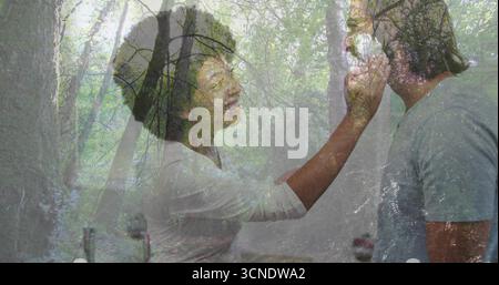 Feeding woman wearing white shirt giving spoonful to man in grey shirt in kitchen, chrome faucet Stock Photo