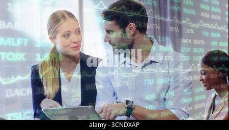 Reviewing three colleagues analyzing stock data in office boardroom, with laptop and chart overlay Stock Photo