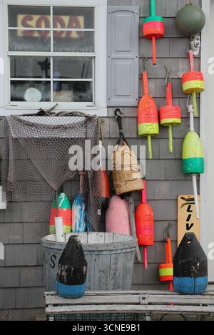 colorful buoys and netting used for lobster traps on side of gray weathered lobster shack Stock Photo