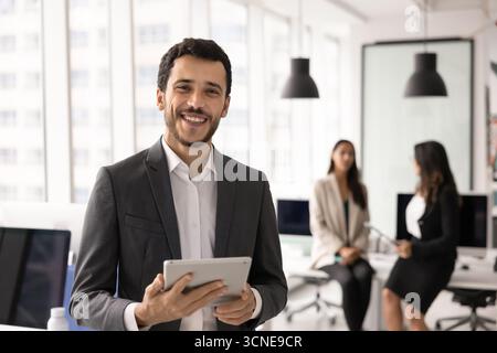 Happy young Middle Eastern project manager man holding tablet Stock Photo