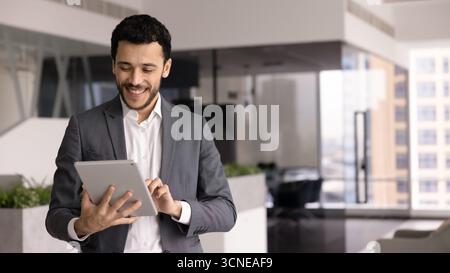 Positive young Middle Eastern male professional working with tablet Stock Photo