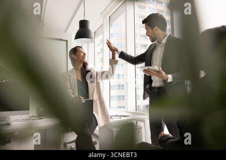 Two diverse excited colleagues making high five gesture Stock Photo