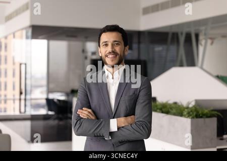 Cheerful Middle Eastern professional man posing in office space alone Stock Photo