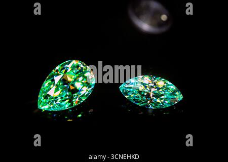 Two green gemstones are displayed on a black background. The stones are of different shapes and sizes, with one being larger and the other smaller. Sc Stock Photo