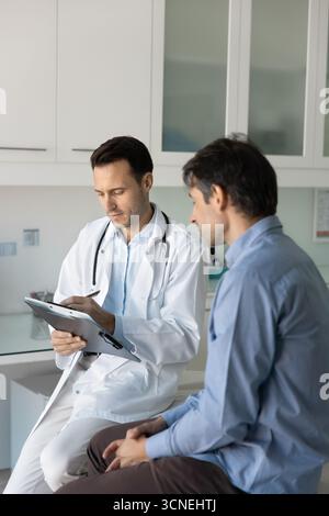 Male patient sitting on couch waiting while doctor make records Stock Photo