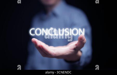 Close up hand presenting conclusion word with light effect on dark background, symbol of final concept, result summary, project closure, success strat Stock Photo