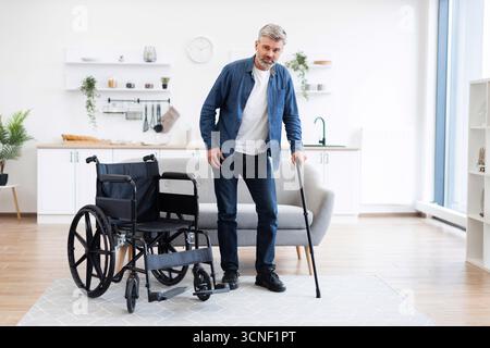 Disabled man practicing walking in modern home using cane for mobility Stock Photo