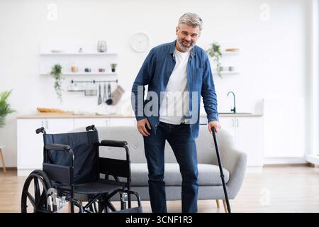 Disabled man practicing walking in modern home using cane for mobility Stock Photo
