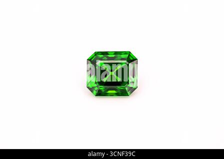 A green gemstone sits on a white background. The stone is cut into an octagon shape Stock Photo