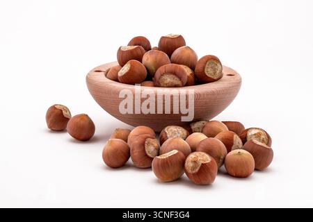 A bowl of nuts is on a white background. The nuts are scattered around the bowl, with some of them being larger and others smaller. The bowl is made o Stock Photo