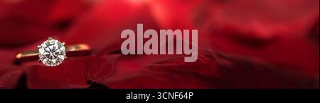 A diamond ring is set in a red velvet cloth. The ring is surrounded by a red background Stock Photo