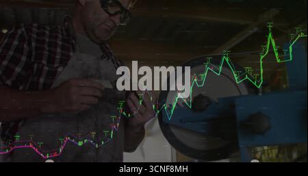 Worker with protective glasses apron filing metal piece in shop grinder, digital charts, copy space Stock Photo