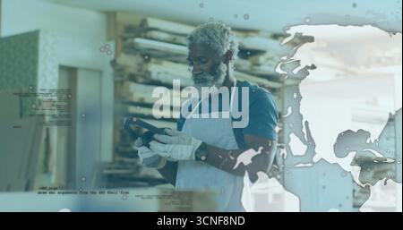 Cobbler wearing gloves holding and examining shoe sole in workshop, with wooden lasts, digital map Stock Photo
