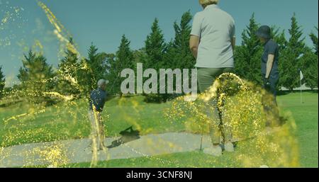 Swinging man hitting bunker shot with golf club on fairway, golfers watching under spark overlay Stock Photo