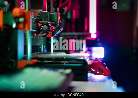 3D printing process neon light modern fabrication showing active 3D printer creating object under colorful studio lighting in high-tech workspace Stock Photo