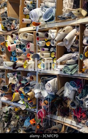 Artisan warehouse with shelves full of rolls of fabrics and textiles for upholstery and furniture. Represents textile production and design. Stock Photo