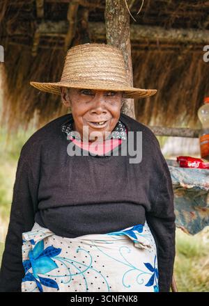 Andringitra National Park, Madagascar - April 27, 2019: Unknown elderly Malagasy woman shopkeeper smiling next to her market stall on the street. Peop Stock Photo