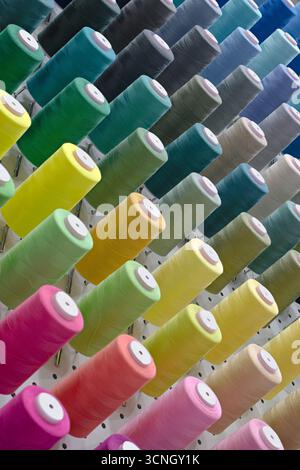 Many spools of thread of different colors, close up shot, abstract textile industry background Stock Photo