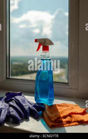 Cleaning spray, cloth and gloves placed on a windowsill, preparing for window washing and household chores Stock Photo