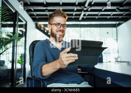 A professional uses a tablet in a modern office that reflects creativity and innovation Stock Photo