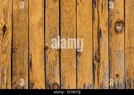 Close up view of weathered yellow painted wood planks showcasing wood grain and knots, forming a rustic textured background Stock Photo