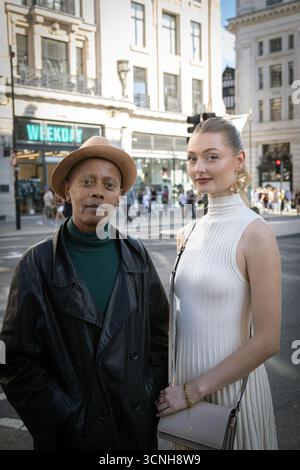 A stylish couple showcasing street style fashion during London Fashion Week, posing on a city street. Stock Photo