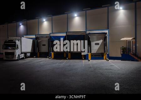 Loading docks of a fruit and vegetable warehouse with a refrigerated truck parked at night Stock Photo