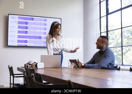 Diverse coworkers gesturing, listening at conference table with vr headset, purple bar chart Stock Photo