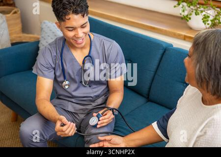 Male nurse checking blood pressure on senior female patient at home Stock Photo