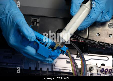Top view of a technician using a vacuum cleaner to suck ink from a printer. Stock Photo