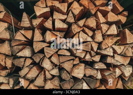 Organic arrangement of chopped split firewood logs forming a wooden backdrop and pattern. Stock Photo