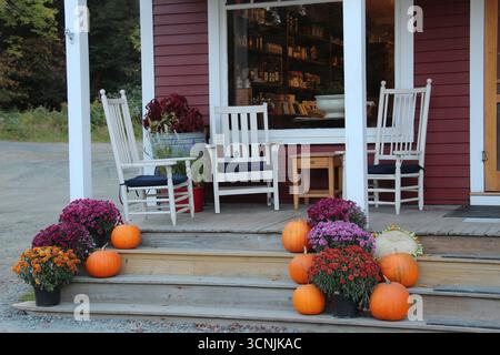 country style porch with white chairs and fall decoration of pumpkins and mums on the stairs Stock Photo