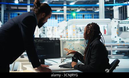 Photovoltaics factory programmer building models of renewable energy generators, presenting progress to manager. Solar panels plant developer builds safe solar cells talking with supervisor, camera A Stock Photo