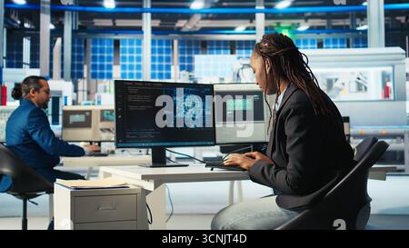 System administrator in photovoltaics factory using AI to diagnose malfunctioning systems. Solar panels manufacturing plant software developer reducing downtime using artificial intelligence, camera A Stock Photo