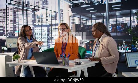 Multicultural group of women in a high powered office meeting, promoting gender equality and female authority in a work environment. Leaders in a men dominated business industry. Camera B. Stock Photo