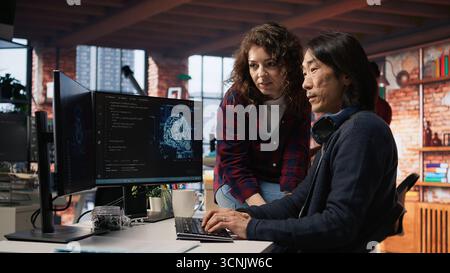Coworkers collaborating in AI tech agency providing software development services. Teamworking startup office colleagues using artificial intelligence to streamline coding process, camera A Stock Photo