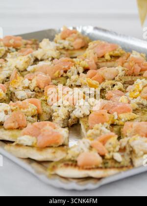 Appetizer toasts with smoked salmon and scrambled eggs on a tray, served during a baptism, wedding, or festive family celebration. Stock Photo