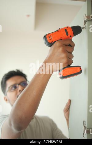Man using a power drill to install cabinet hardware Stock Photo