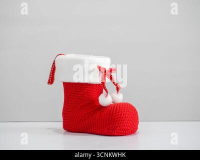 Red Christmas boot with white fur and ribbon bow decoration on white background. Festive holiday ornament symbolizing Santa gift, Christmas celebratio Stock Photo
