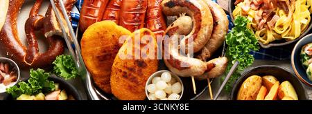 Various austrian dishes- schnitzel, sausages, potatoes, Knodel, salad and sauces on a light background. Top view. Panorama. Stock Photo