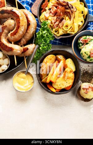 Various austrian dishes- schnitzel, sausages, potatoes, Knodel, salad and sauces on a light background. Top view. Copy space. Stock Photo