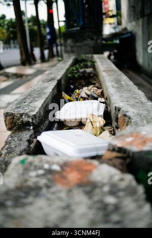 discarded disposable styrofoam lunch box on drainage Stock Photo
