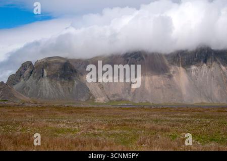 Stokksnes Iceland, view across fields of grass to mountains shrouded in clouds Stock Photo