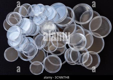 Transparent Plastic Coin Capsules Scattered on Black Background Stock Photo
