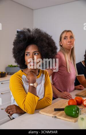 Diverse female friends chopping vegetables on wooden board in kitchen near glass drink Stock Photo