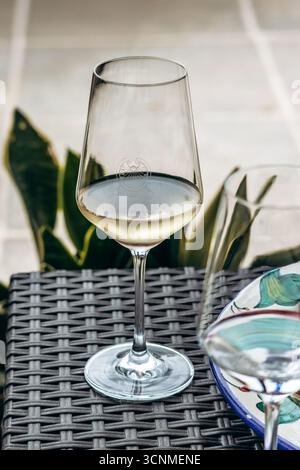 Ta' Qali, Malta – April 14, 2025: A close-up of a glass of white wine served during a tasting at Meridiana Wine Estate, placed on a wicker table next Stock Photo