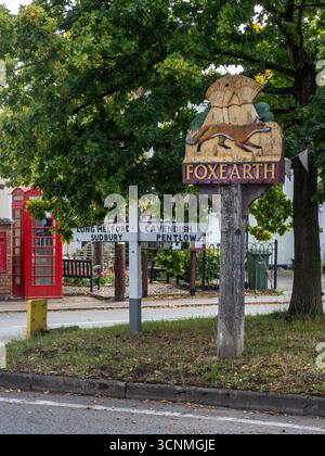 Traditional painted village sign for Foxearth, Essex, UK, depicting a fox and wheatsheaves symbolising the rural heritage of the village. Stock Photo