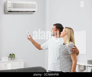 Couple using remote to control air conditioner at home Stock Photo