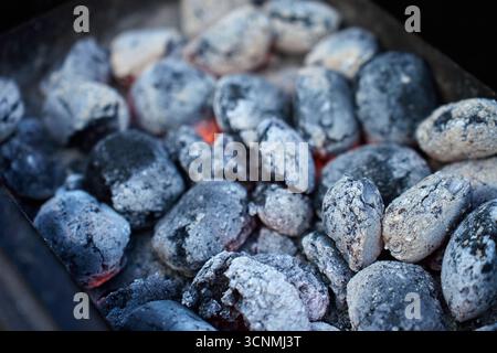 Close-up of hot charcoal briquettes burning in grill, ready for cooking. Concept of outdoor barbecue, summer picnics and grilling Stock Photo